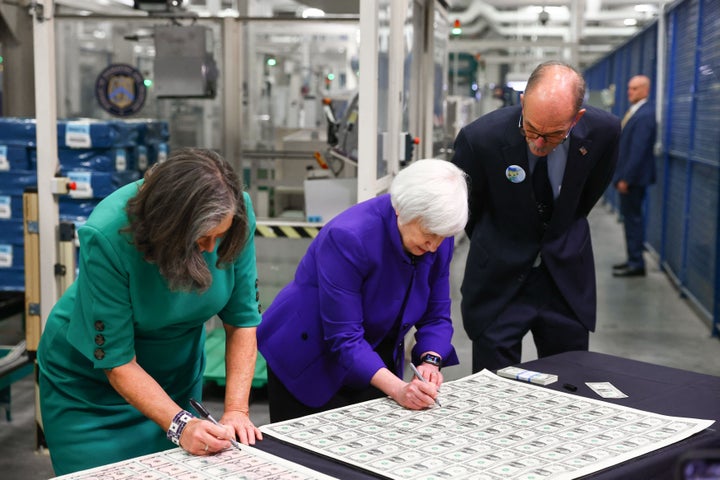 Yellen and Malerba sign $1 bills.