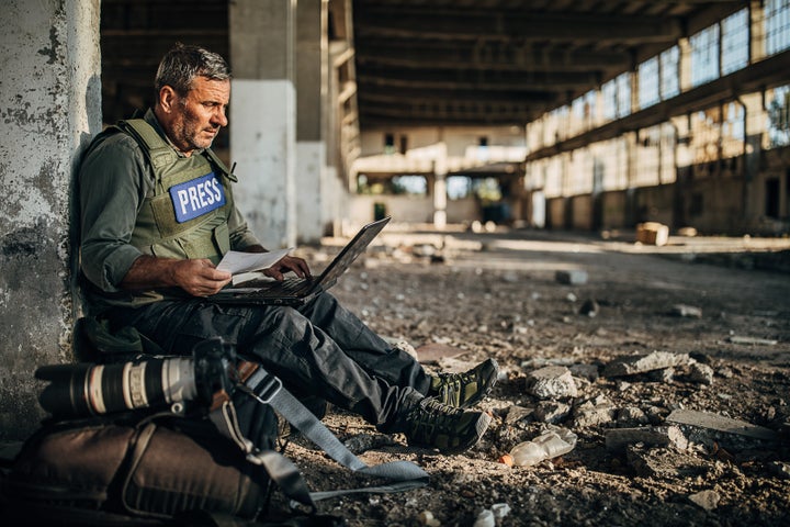 One man, war journalist with using laptop at the place of action, in war zone.