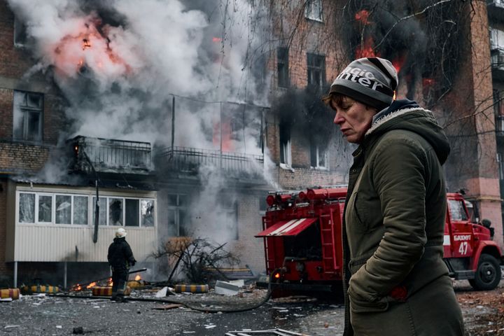 A local resident walks past her burning house on Dec. 7, after Russian shelling.