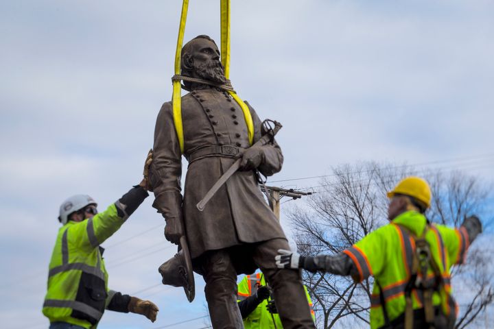 Workers begin to lay the bronze statue of General A.P. Hill onto a flatbed truck on Monday in Richmond. Workers are still planning to exhume the remains of the general, which are located inside the base of the statue.