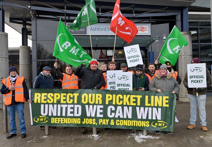 Rail workers hold banners and union flags during the strike over pay, job security and working conditions