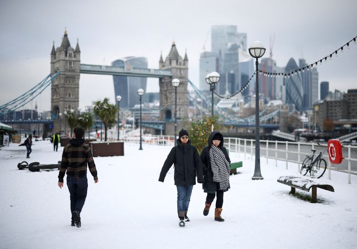 People walk on a snow-covered pathway near the Tower Bridge, as cold weather continues in London, Britain, December 12, 2022. REUTERS/Henry Nicholls