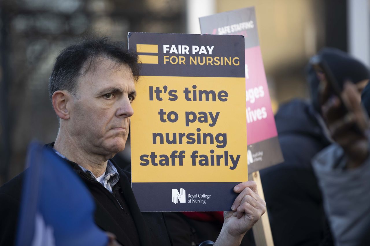  A man holds a signboard as nurses demonstrate against salary increase offered under inflation and poor working conditions at St. Thomas' Hospital, London, United Kingdom on December 15, 2022. 