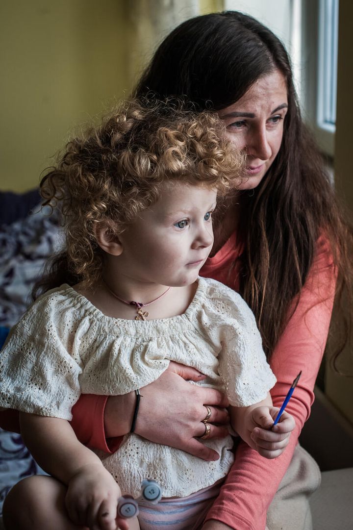 Elena*, 36, sits for a portrait with her two-year-old daughter Vira* in their flat in Suceava county, northern Romania