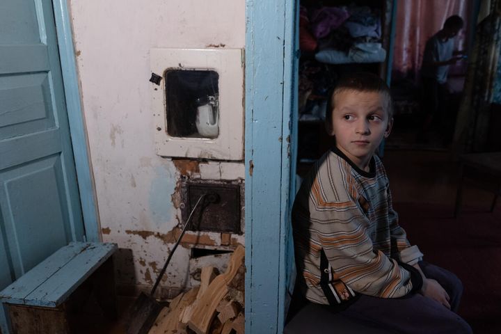 Dmytro*'s brother Taras*, four, sits by the wall behind the heating stove at home near Chernihiv, Ukraine.