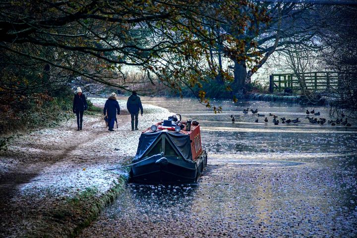 A moored canal boat on a frozen Bridgewater canal in Lymm, Cheshire.