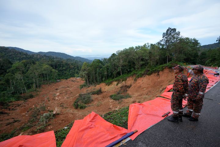 Fire and rescue team members look down on a landslide in Batang Kali, Malaysia on Saturday. The landslide left more than a dozen of people dead.