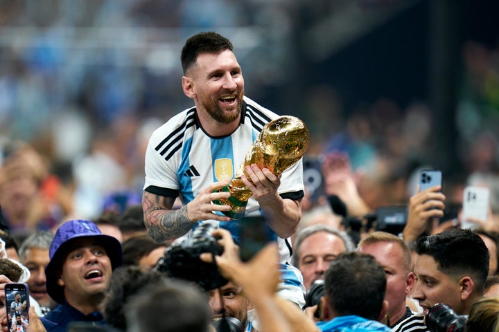 Lionel Messi celebrates with the World Cup trophy with supporters while on the shoulders of Sergio 'Kun' Aguero.