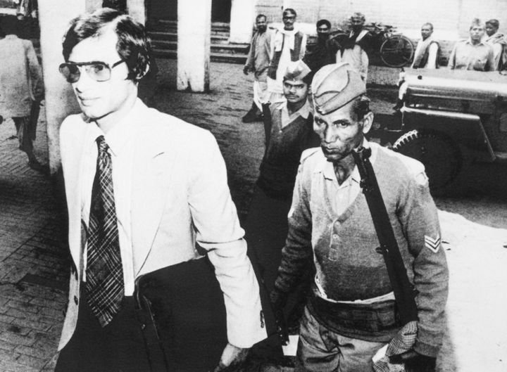 Ο εγκληματίας Σαρλς Σομπράζ, συνοδευόμενος από έναν Ινδό αστυνομικό με τουφέκια, εισέρχεται στο δικαστήριο στις 3 Μαρτίου 1982, στο Βαρανάσι της Ινδίας, 600 χιλιόμετρα βορειοδυτικά της Καλκούτας.