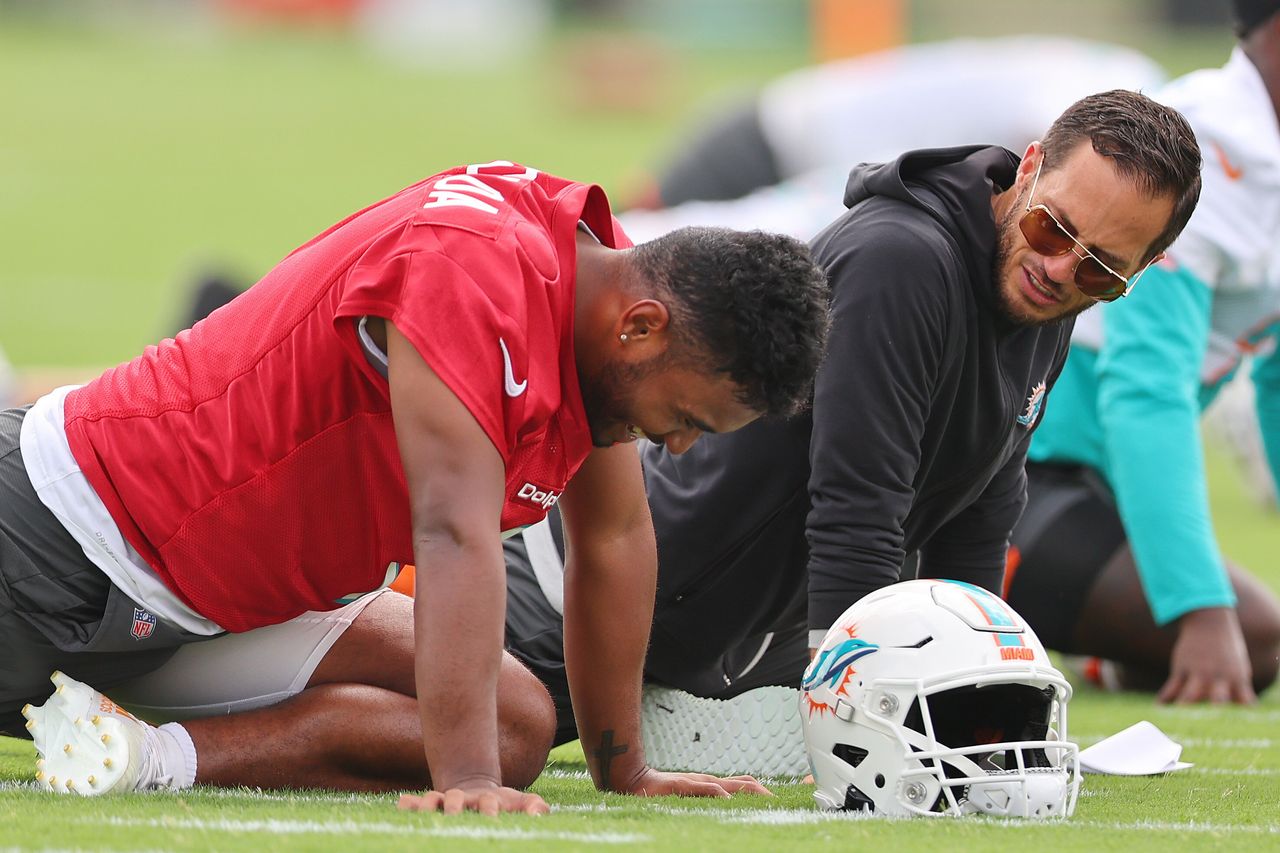 Mike McDaniel (right), the head coach of the Miami Dolphins, stretches with quarterback Tua Tagovailoa during training on July 27 in Miami Gardens, Florida.