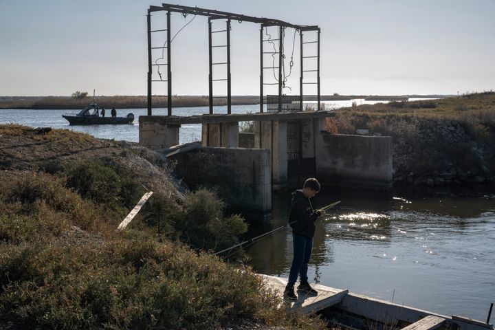 Ένα αγόρι ψαρεύει ενώ συνοριοφύλακες περιπολούν σε σκάφους κατά μήκος του ποταμού Έβρου που αποτελεί φυσικό σύνορο μεταξύ Ελλάδας και Τουρκίας, την Κυριακή 30 Οκτωβρίου 2022.
