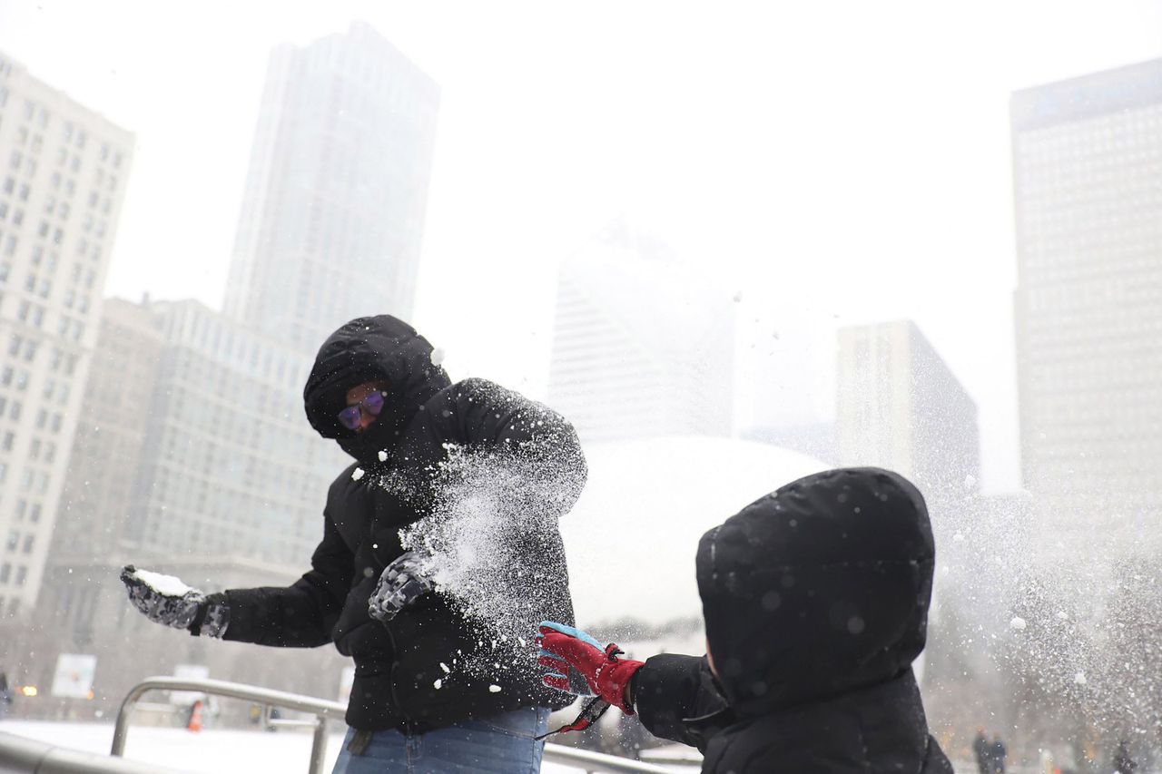 Andres Garduno and his son Matteo Jimenez Garduno, both from Mexico, have a snowball fight during the winter storm at Chicago's Millennium Park ice rink on Thursday.