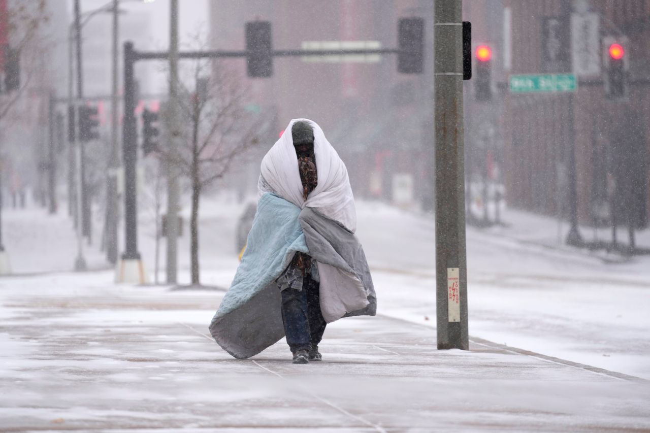 A pedestrian in St. Louis uses a blanket to fend off the sub-freezing cold Thursday.