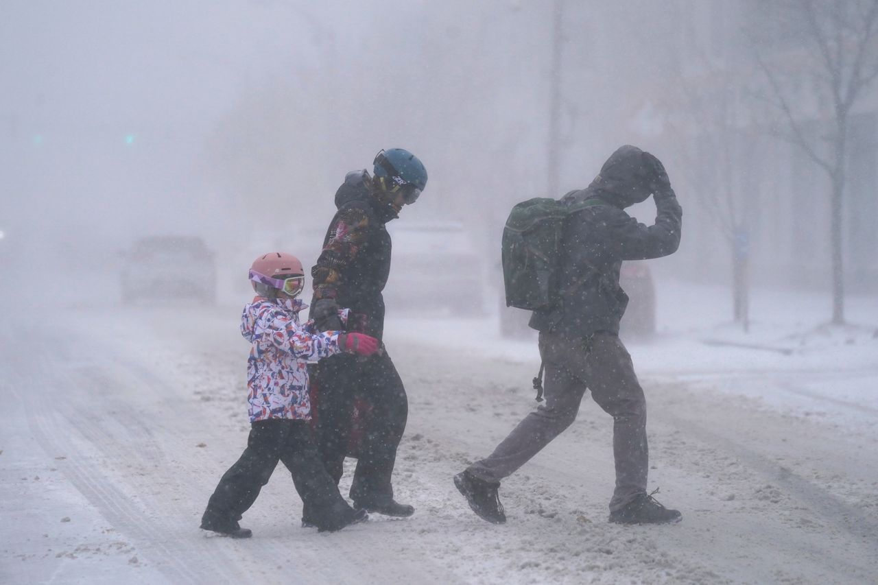 A family bundled up in winter clothes makes their way across the street in Buffalo, New York, on Friday after stocking up on supplies at the grocery store.