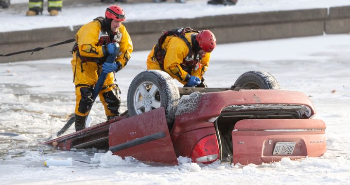 Kansas City fire department rescue workers work to recover a minivan that went into Brush Creek in Kansas City, Mo., on Thursday, Dec. 22, 2022. Police say the driver lost control of the minivan on an icy street and the vehicle went down an embankment and overturned before submerging in Brush Creek. The driver was pulled from the creek but died later at a hospital. (Nick Wagner/The Kansas City Star via AP)