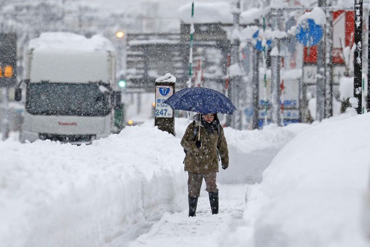 A woman makes her way through heavy snow in Uonua, Niigata prefecture, northern Japan.(Kyodo News via AP)