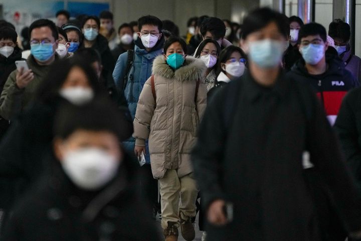 Masked commuters walk through a walkway in between two subway stations as they head to work during the morning rush hour in Beijing, Tuesday, Dec. 20, 2022. China continues to adapt to an easing of strict virus containment regulations. About three years ago, the original version of the coronavirus spread from China to the rest of the world and was eventually replaced by the delta variant, then omicron and its descendants, which continue plaguing the world today. (AP Photo/Andy Wong, File)