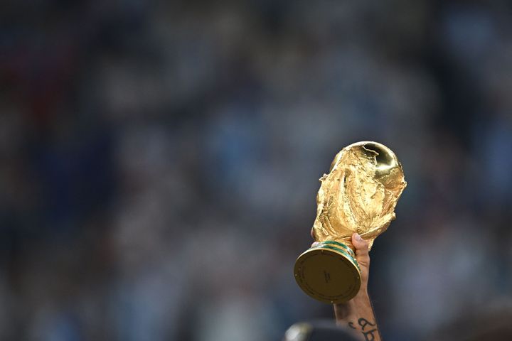 アルゼンチンの選手によって高く掲げられた、FIFAワールドカップ2022優勝トロフィー