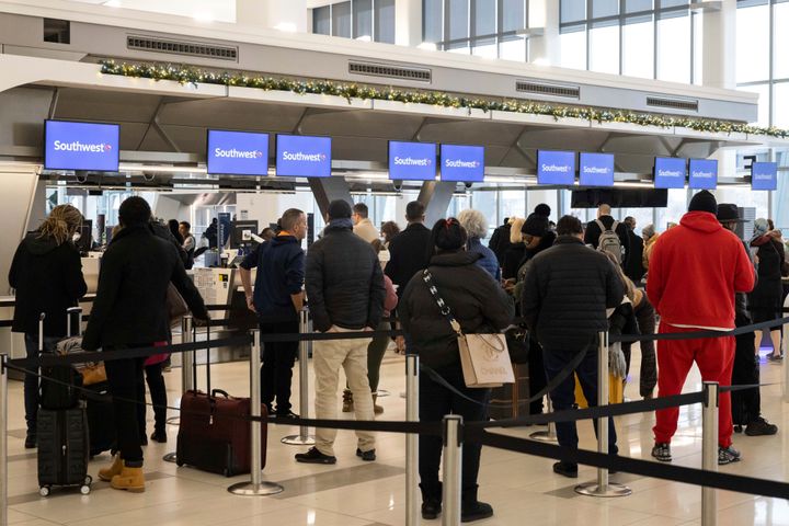 Passengers wait in line to check in for their flights at Southwest Airlines service desk at LaGuardia Airport, Tuesday, Dec. 27, 2022, in New York.