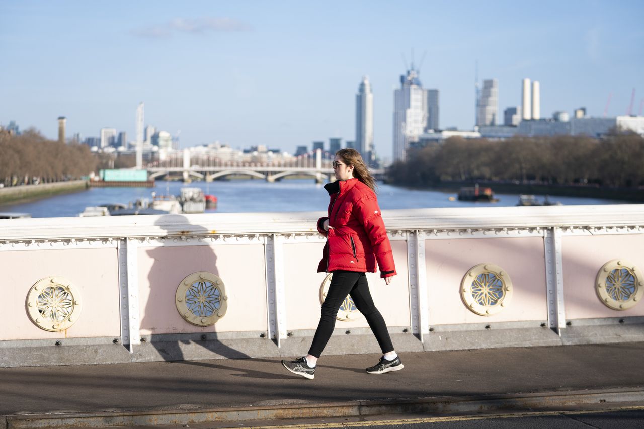 A woman walks across Albert Bridge in the afternoon sunshine in Battersea, London on January 30, 2022.