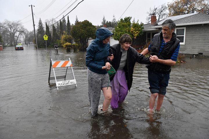 Nurse Katie Leonard, left, helps Scott Mathers, right, as they rescue Mathers' mother, Patsy Costello, 88, after she was trapped in her vehicle for more than an hour on Astrid Drive in Pleasant Hill, Calif., on Saturday, Dec. 31. 2022. Costello drove her car down the flooded road thinking she could make it when she stopped in two feet of water.  After two hours the water had receded about a foot making her rescue easier.  The police were called but stayed and watched after calling a tow truck to help pull the car out of the water.  Nurse Katie Leonard, of Pleasant Hill, lives down the block and used her kayak to bring Costello hot tea, blankets, food and a phone to call a friend.  (Jose Carlos Fajardo/Bay Area News Group via AP)