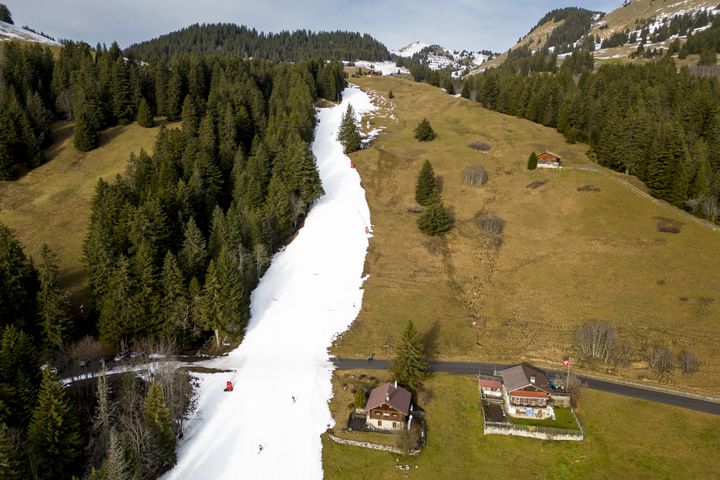 Skiers speed down a slope with artificial snow in the middle of a snowless field in the Alpine resort of Villars-sur-Ollon, Switzerland, on Saturday.