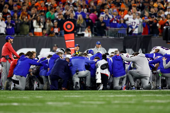 Buffalo Bills players and staff kneel together in solidarity after Damar Hamlin collapsed on the field during a cardiac arrest. 
