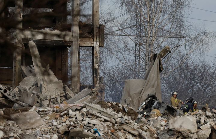 Workers remove debris of a destroyed building purported to be a vocational college used as temporary accommodation for Russian soldiers, dozens of whom were killed in a missile strike.