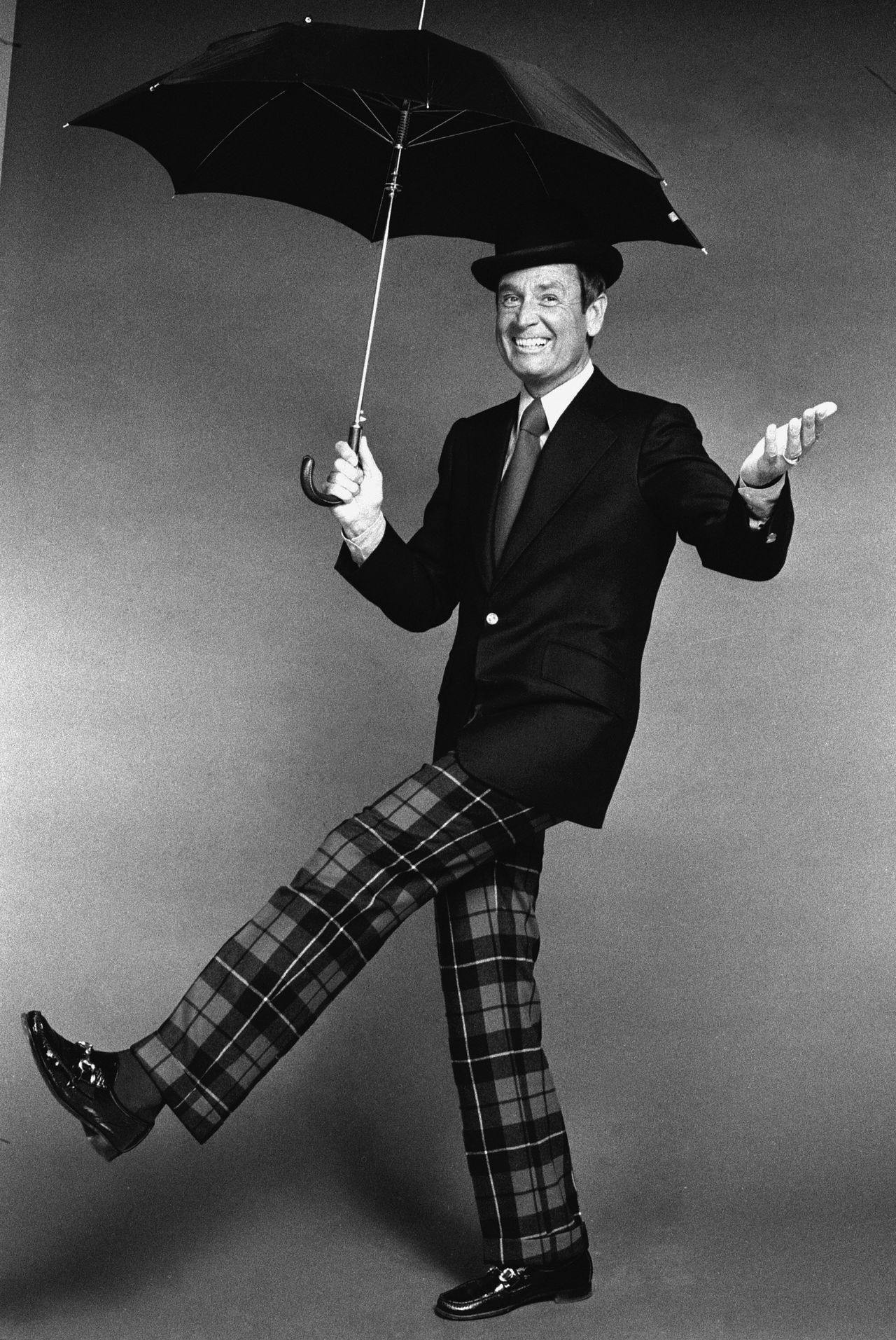Barker wears a bowler hat and plaid pants as he cavorts with an umbrella on Dec. 6, 1973.