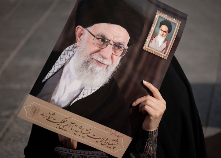 Μια Ιρανή καλυμμένη με μπούρκα γυναίκα κρατά πορτρέτα του Ανώτατου Ηγέτη του Ιράν, Αγιατολάχ Αλί Χαμενεΐ και του αείμνηστου ηγέτη Αγιατολάχ Ρουχολάχ Χομεϊνί, ενώ παρευρίσκεται σε συγκέντρωση διαμαρτυρίας ενάντια στο γαλλικό σατιρικό εβδομαδιαίο περιοδικό Charlie Hebdo που επανδημοσίευσε μια γελοιογραφία του προφήτη Μοχάμεντ, στη νότια Τεχεράνη στις 10 Σεπτεμβρίου, 10, 2020.