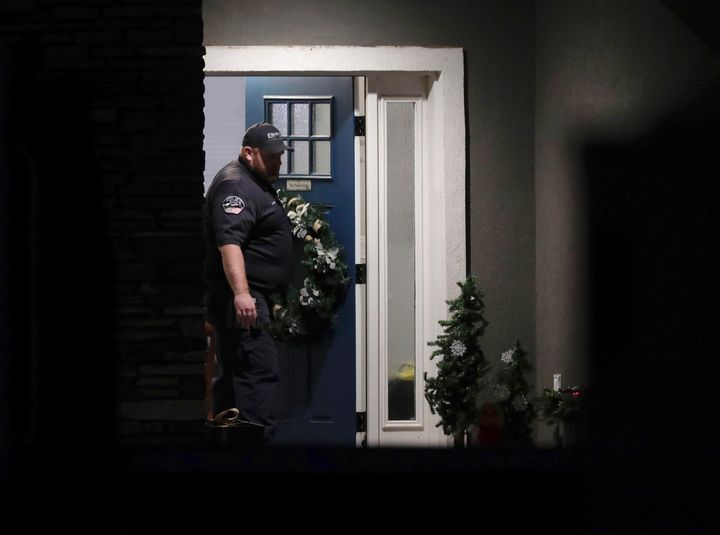 A law enforcement official stands at the front door of the Enoch, Utah home where eight family members were found dead from gunshot wounds on Wednesday. The five children in the family attended schools in the Iron County School District, officials said in a letter sent to parents.