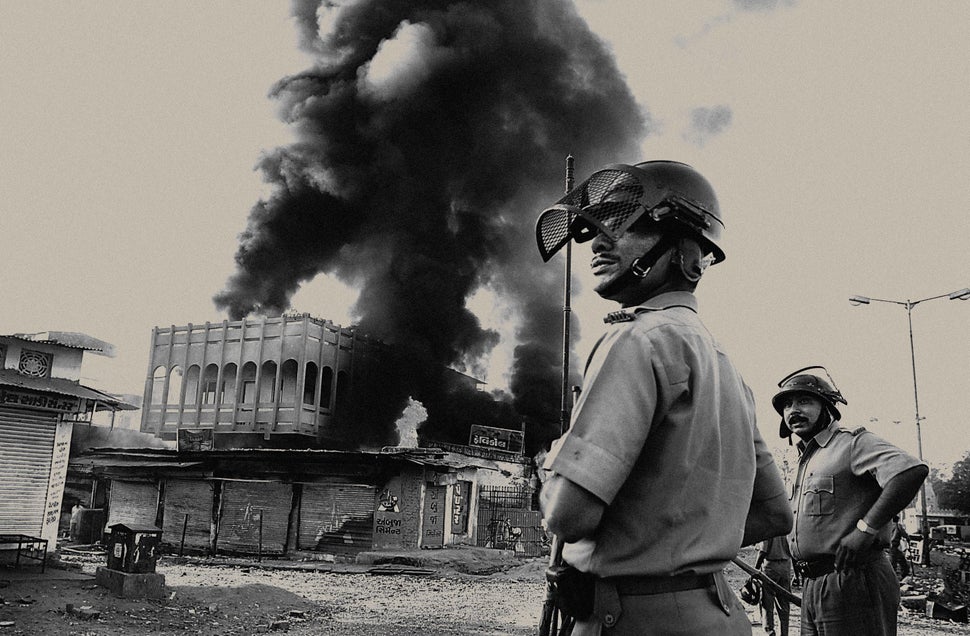 Indian state police watch a Muslim-owned shop burn, March 1, 2002, in Ahmedabad, India.