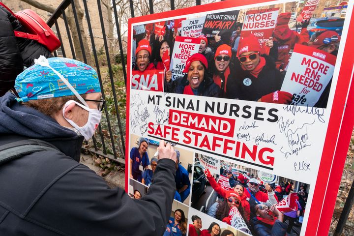 FILE - Zach Clapp, a nurse in the Pediatric Cardiac ICU at Mount Sinai Hospital signs a board demanding safe staffing during a rally by NYSNA nurses from NY Presbyterian and Mount Sinai, Tuesday, March 16, 2021, in New York. Negotiations to keep 10,000 New York City nurses from walking off the job headed Friday, Jna. 6, 2023, into a final weekend as some major hospitals braced for a potential strike by sending ambulances elsewhere and transferring such patients as vulnerable newborns. (AP Photo/Mary Altaffer, File)