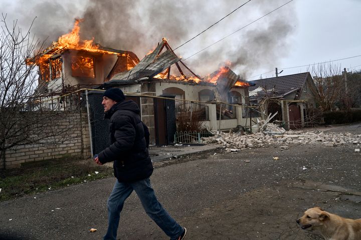 A local resident runs past a burning house hit by the Russian shelling in Kherson, Ukraine, on the Orthodox Christmas Eve, Friday, Jan. 6. (AP Photo/LIBKOS)