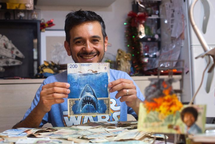Ο καλλιτέχνης Σέρχιο Ντίας κρατά χαρτονομίσματα αργεντίνικων πέσος και ένα δολάριο ΗΠΑ που απεικονίζουν την ταινία του Στίβεν Σπίλμπεργκ "Τα σαγόνια του καρχαρία" καυτηριάζοντας τον συνεχώς αυξανόμενο πληθωρισμό.
