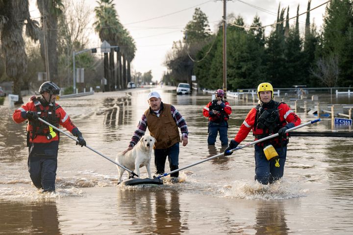 San Diego firefighters help Humberto Maciel rescue his dog from his flooded home in Merced, California, on January 10, 2023. (Photo by JOSH EDELSON/AFP via Getty Images)