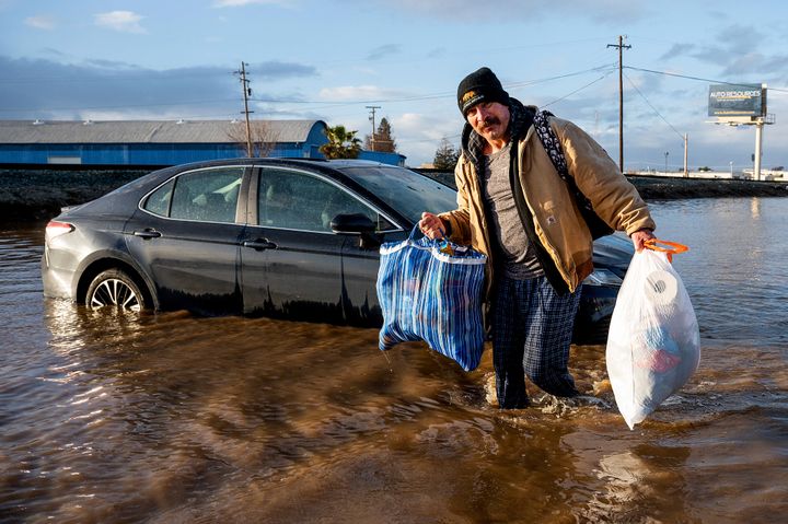 Jesus Torres carries belongings from his flooded Merced, Calif., home on Tuesday, Jan. 10, 2023. (AP Photo/Noah Berger)