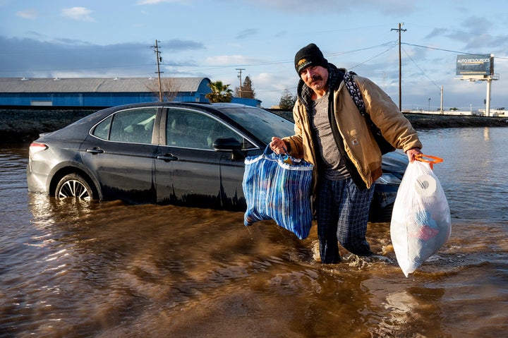 Jesus Torres carries belongings from his flooded Merced, Calif., home on Tuesday, Jan. 10, 2023. (AP Photo/Noah Berger)