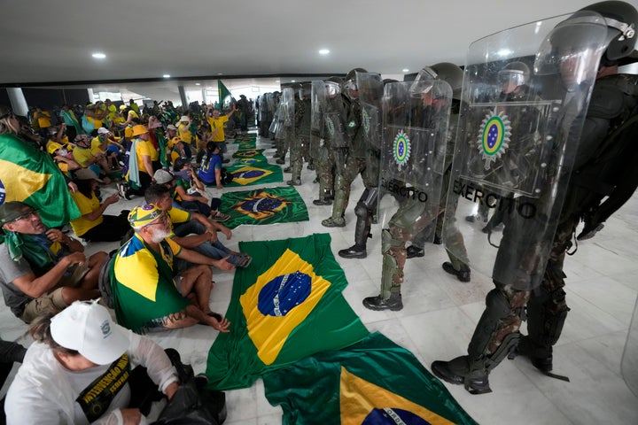Supporters of Brazil's former President Jair Bolsonaro sit in front of police inside Planalto Palace after storming it, in Brasilia, Brazil, on Jan. 8, 2023. Planalto is the official workplace of the president of Brazil.