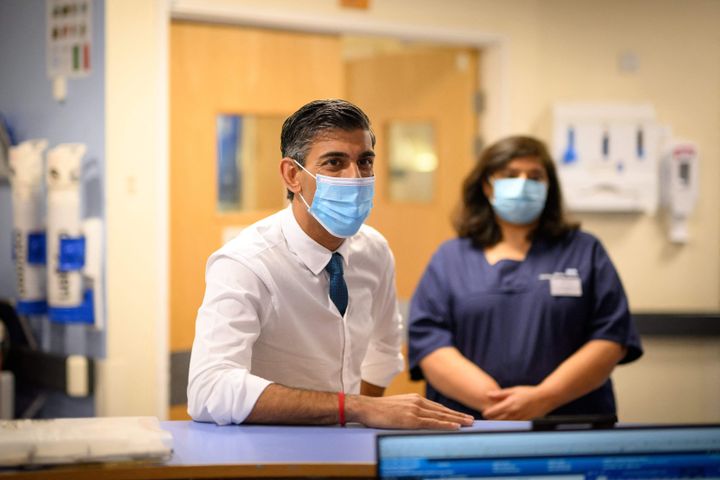 Britain's Prime Minister Rishi Sunak, wearing a face covering, speaks with nursing staff during his visit to Croydon.