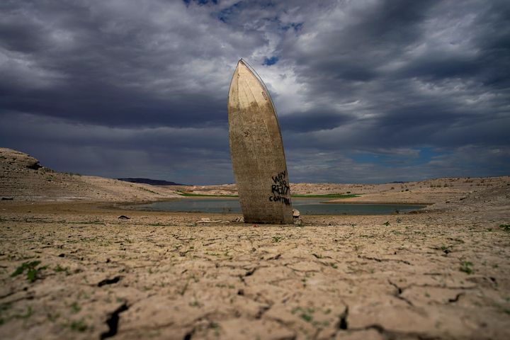 A formerly sunken boat stands upright with its stern buried in the mud along the shoreline of Lake Mead at the Lake Mead National Recreation Area on June 22, 2022, near Boulder City, Nevada.