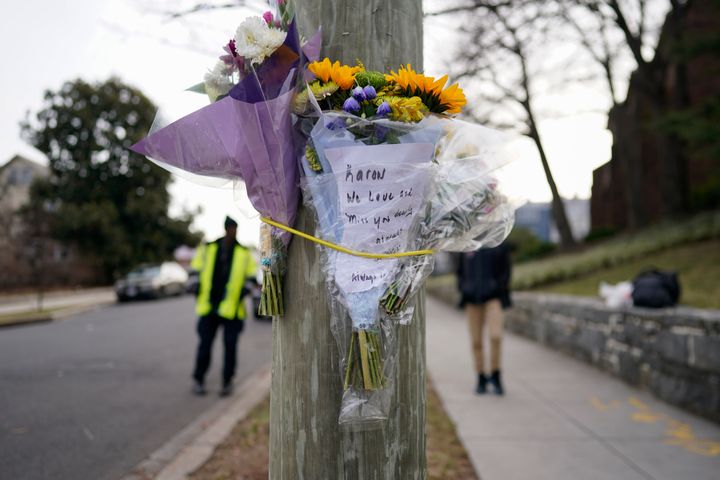 A boy walks to school Tuesday as a crossing guard stands by near flowers that are secured to a pole as a memorial to Karon Blake, 13, at Quincy Street NE and Michigan Avenue NE in the Brookland neighborhood of Washington. The note says, "Karon, we love and miss you dearly."