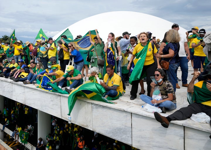 Des manifestants, partisans de l'ancien président brésilien Jair Bolsonaro, se tiennent sur le toit du bâtiment du Congrès national après l'avoir pris d'assaut, à Brasilia, au Brésil, le dimanche 8 janvier 2023. (AP Photo/Eraldo Peres)