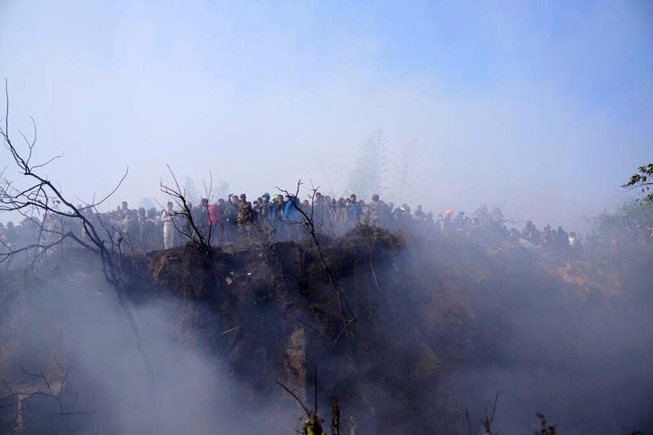 Locals watch the wreckage of a passenger plane in Pokhara, Nepal on Sunday.