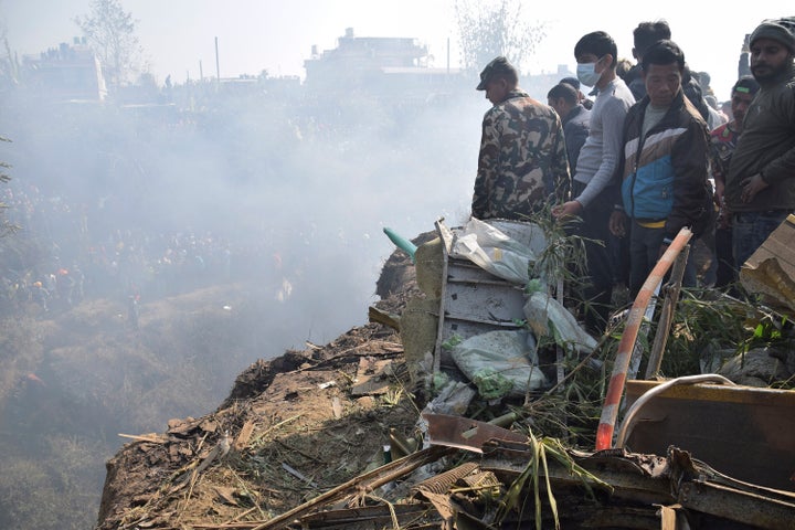 Nepalese rescue workers and civilians gather around the wreckage of a passenger plane that crashed in Pokhara, Nepal, Sunday, Jan. 15, 2023. Authorities in Nepal said 68 people have been confirmed dead after a regional passenger plane with 72 aboard crashed into a gorge while landing at a newly opened airport in the resort town of Pokhara. It's the country's deadliest airplane accident in three decades. (AP Photo/Krishna Mani Baral)