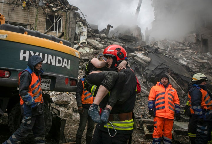 Emergency workers carry a wounded woman after a Russian rocket hit a multistory building on Saturday in Dnipro, Ukraine, Sunday, Jan. 15, 2023. (AP Photo/Yevhenii Zavhorodnii)