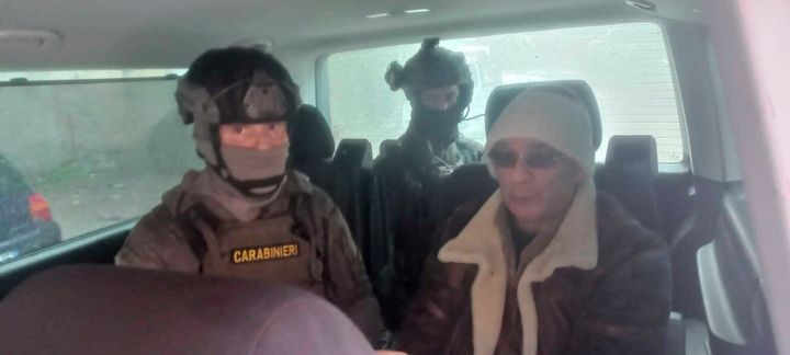 In this Italian Carabinieri handout photo made available on Jan. 16, 2023, top Mafia boss Matteo Messina Denaro, right, is seen in a car with Italian Carabinieri officers soon after his arrest at a private clinic in Palermo, Sicily, after 30 years on the run.
