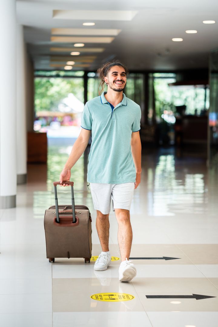 Portrait of young happy man arriving in hotel