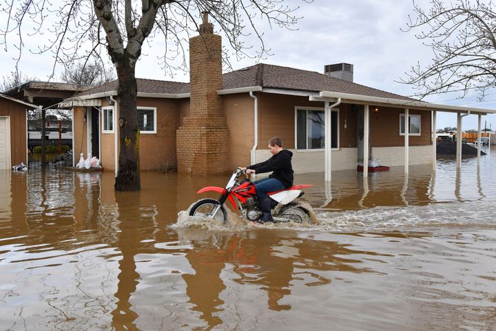 Devan Beard, 13, of Brentwood, rides his off-road motorcycle around his flooded home on Bixler Road in Brentwood, Calif., on Jan. 16, 2023. 