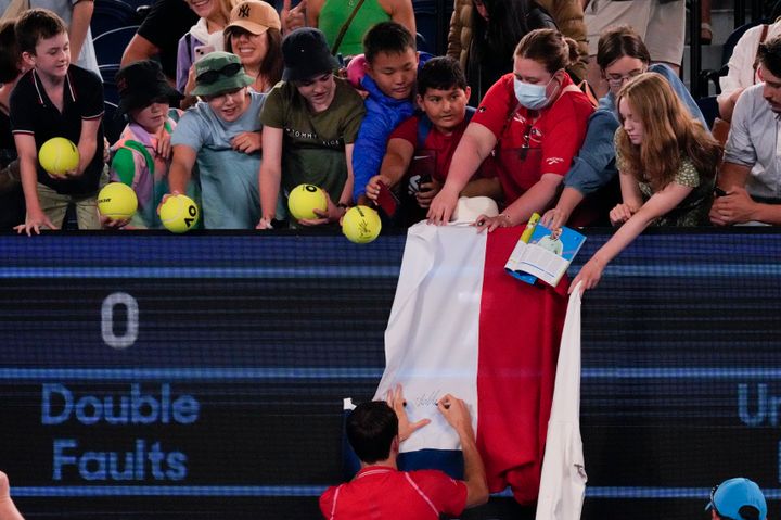 Daniil Medvedev of Russia autographs a Russian flag after defeating Marcos Giron of the U.S. in their first round match at the Australian Open.